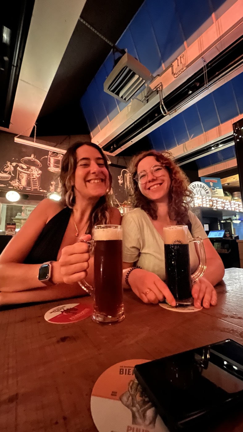 Duas viajantes a brindar com cerveja num bar de uma cervejaria