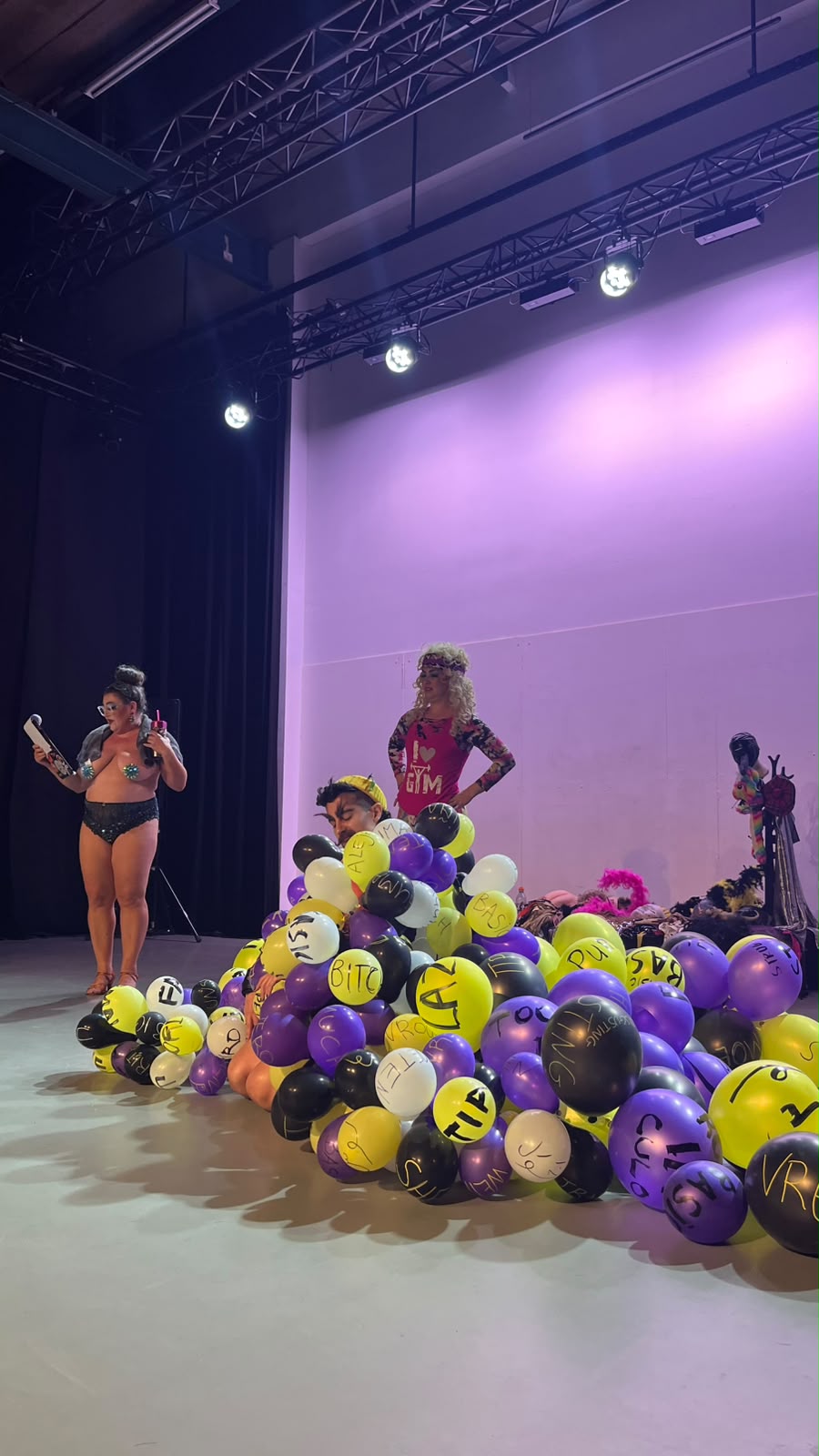 Artistas em palco num espetáculo com uma pilha de balões com palavras escritas
