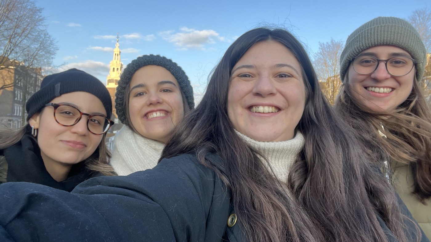 Selfie de quatro viajantes ao sol, junto a um canal de Amesterdão