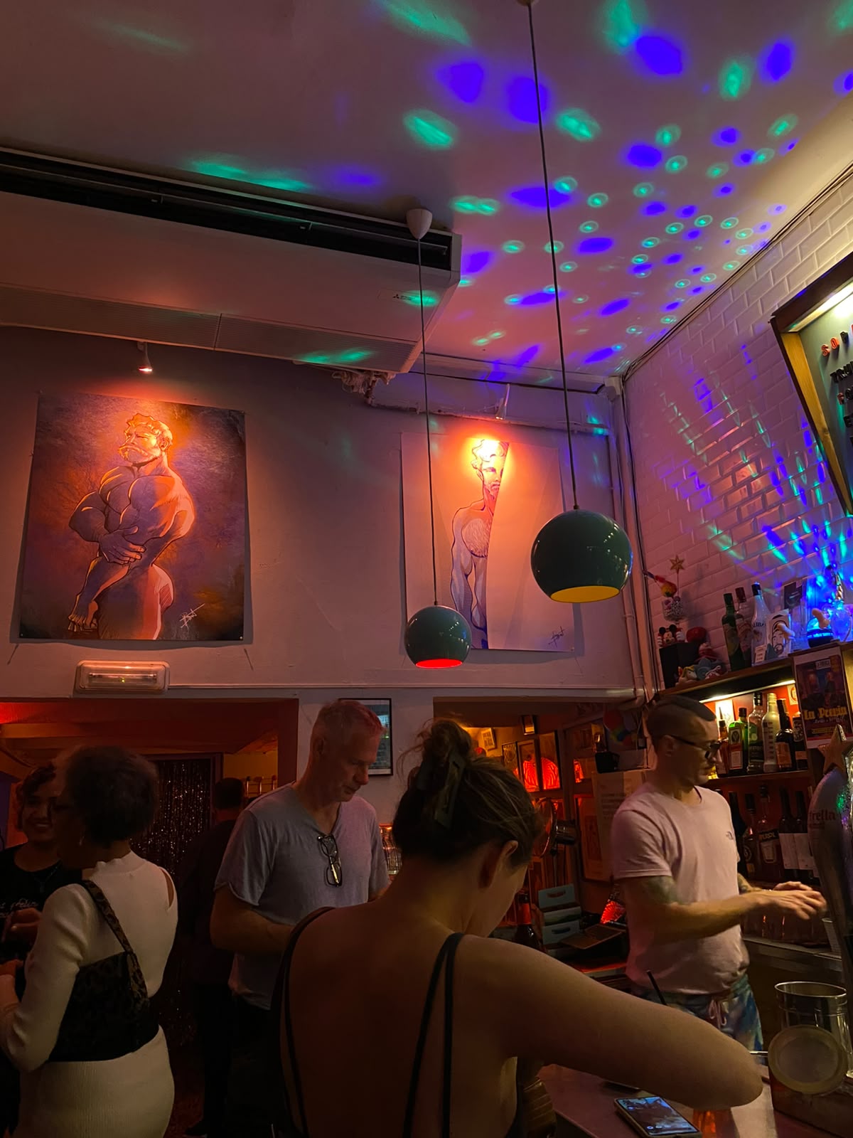 Bar queer em Barcelona com luzes de discoteca e ilustrações de nus masculinos na parede