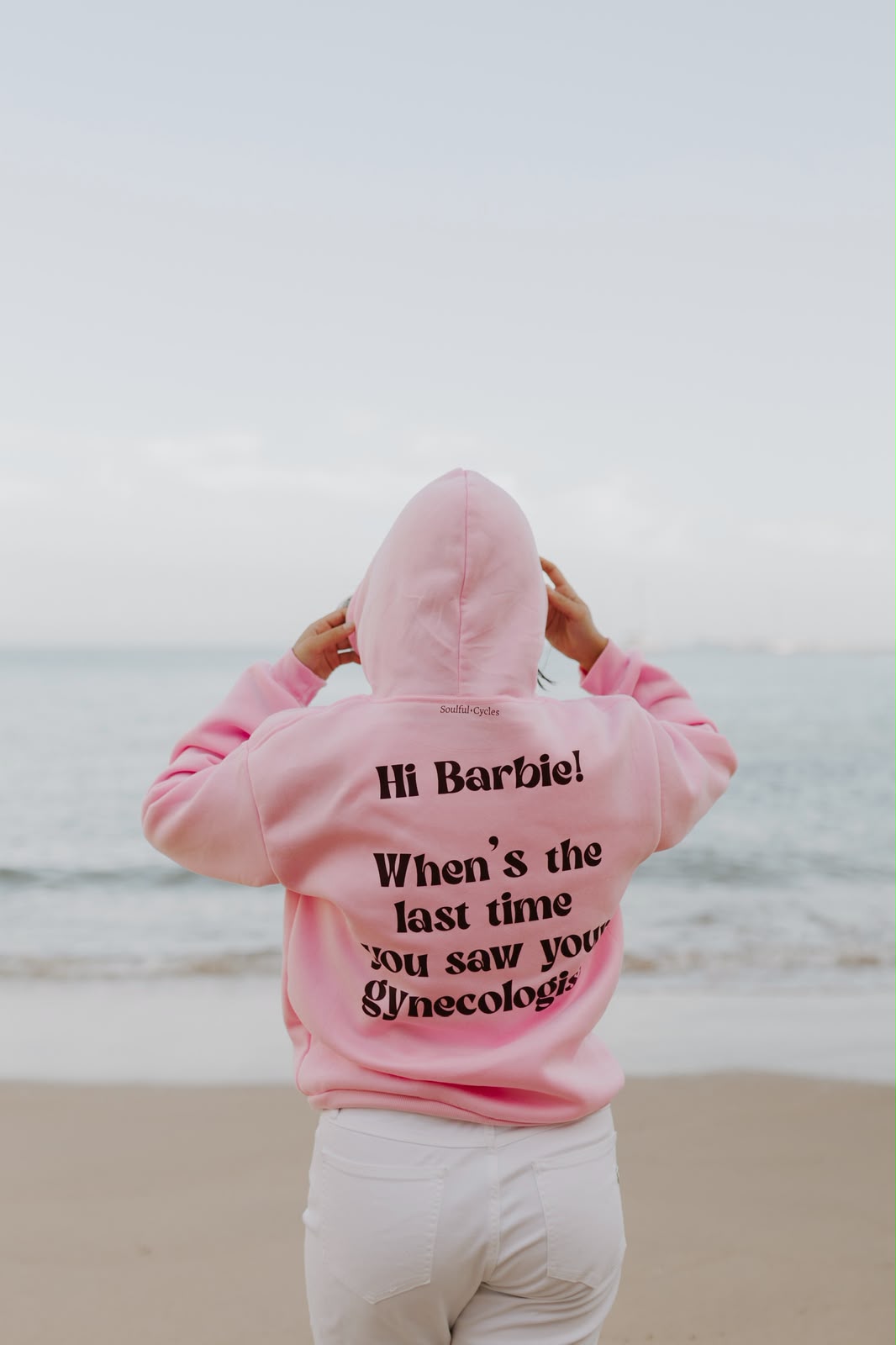 Costas de uma hoodie cor-de-rosa com a frase 'Hi Barbie! When's the last time you saw your gynecologist?'