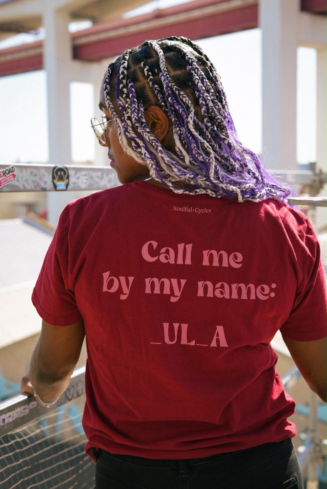 Costas de uma t-shirt vermelha com a frase 'Call me by my name: _UL_A'