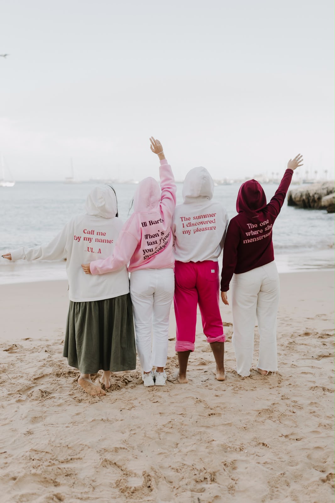 As mesmas quatro amigas de costas, a mostrar as frases nas costas das hoodies