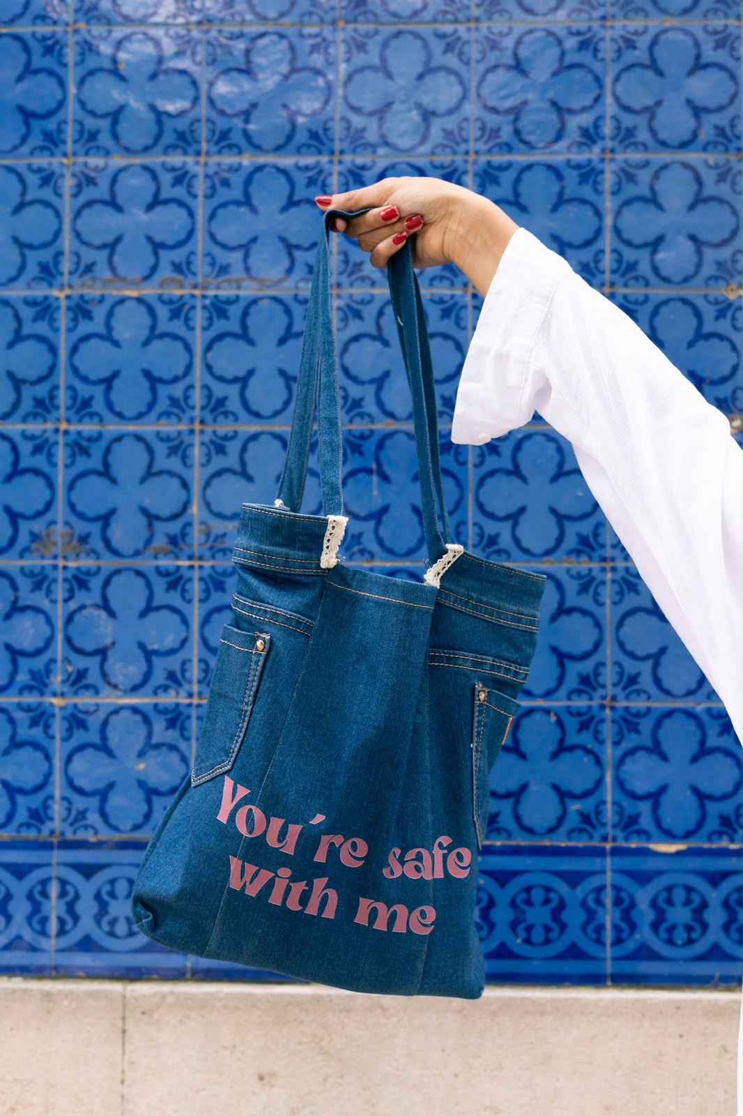 Tote bag de ganga com a frase 'You're safe with me', em frente a azulejos azuis