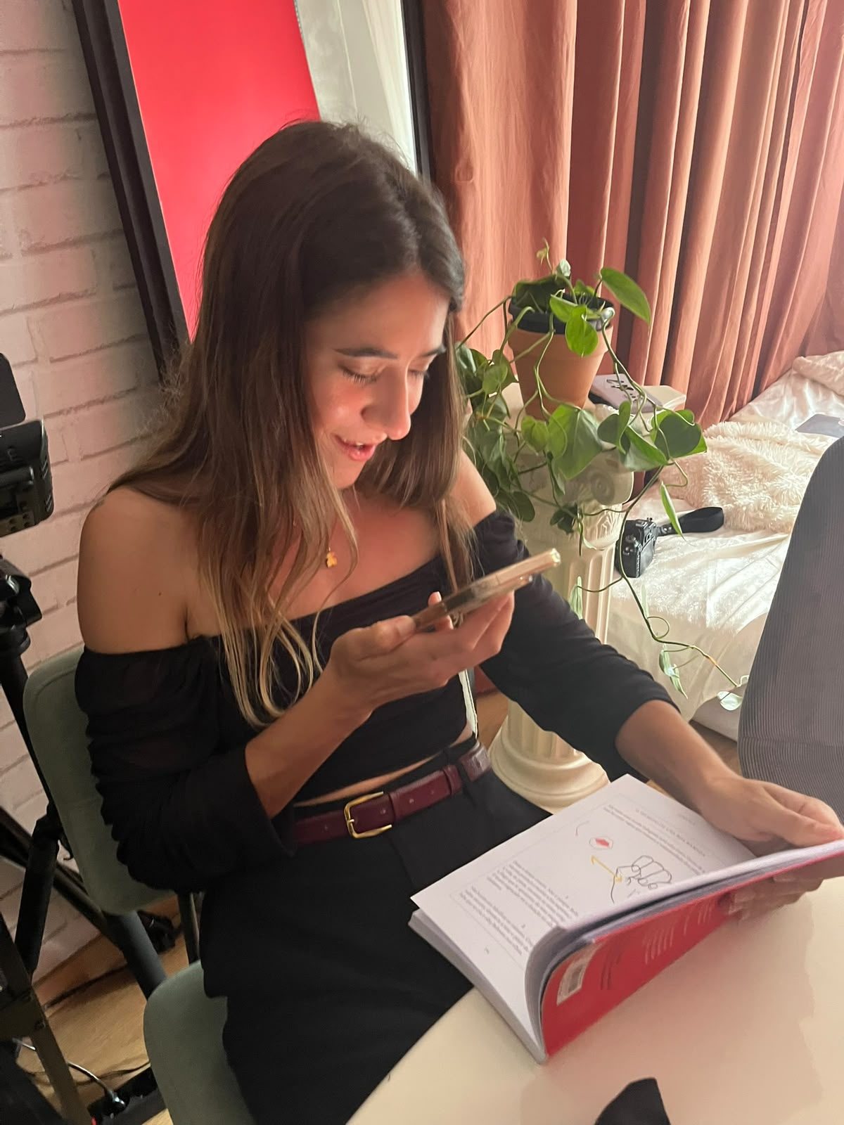 Mariana a sorrir enquanto lê um livro e segura o telemóvel, numa despedida de solteira