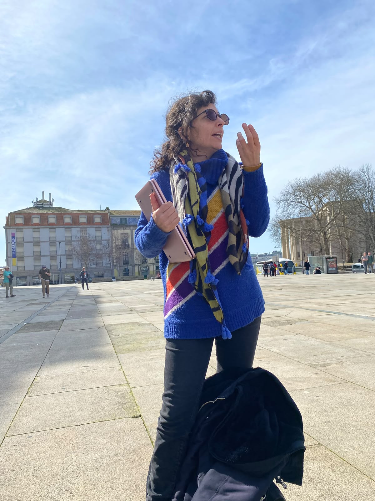 Guia com uma camisola às riscas arco-íris a falar numa praça do Porto