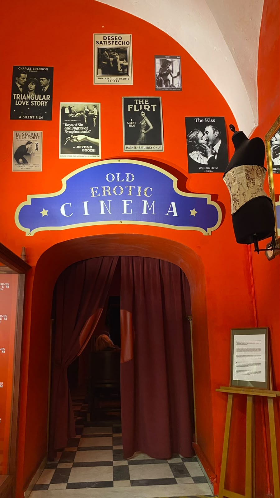 Entrada do antigo cinema erótico, com cartazes antigos de filmes eróticos numa parede laranja