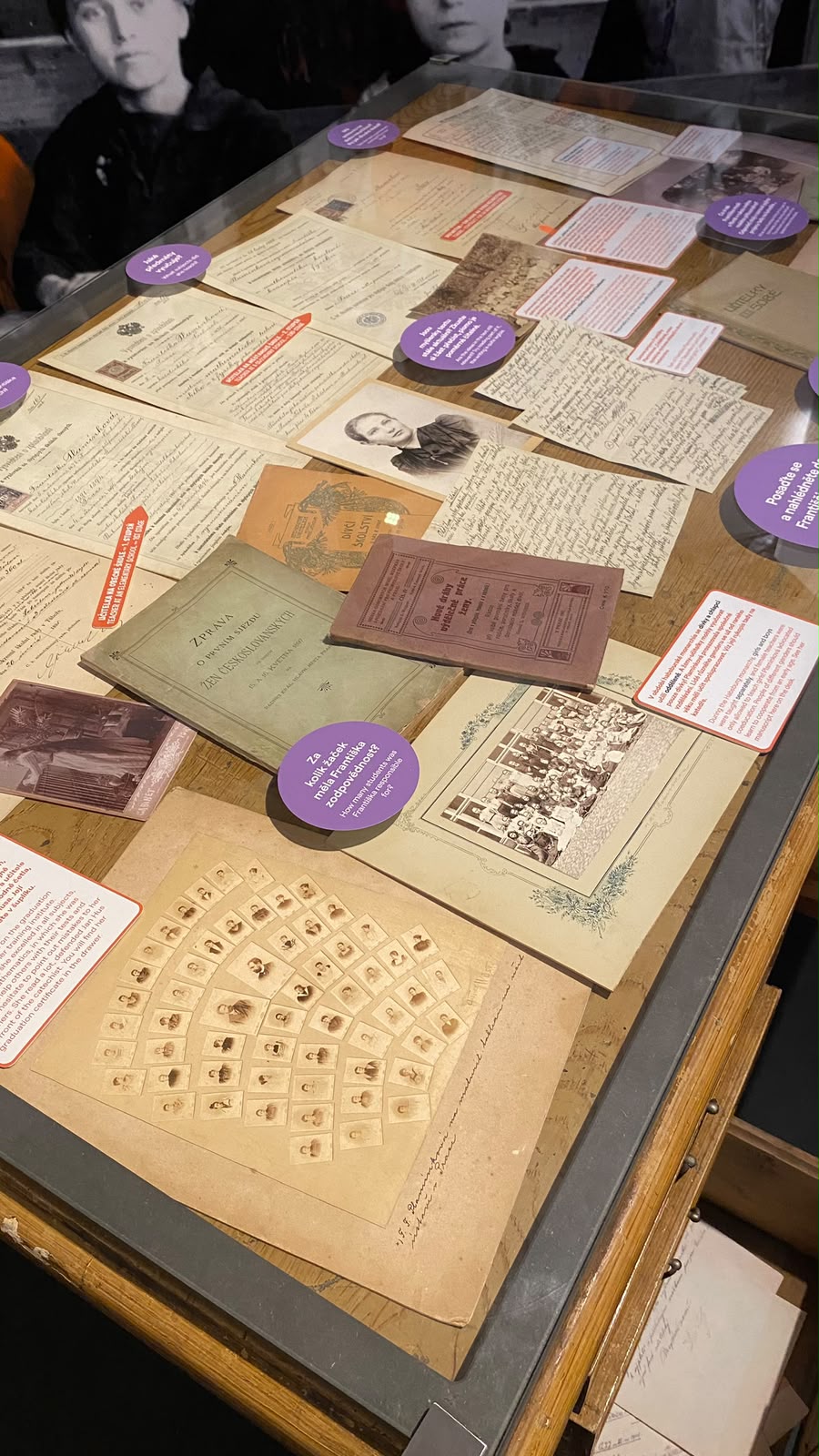 Vitrine de museu com documentos, cartas e fotografias antigas sobre a educação das mulheres checas
