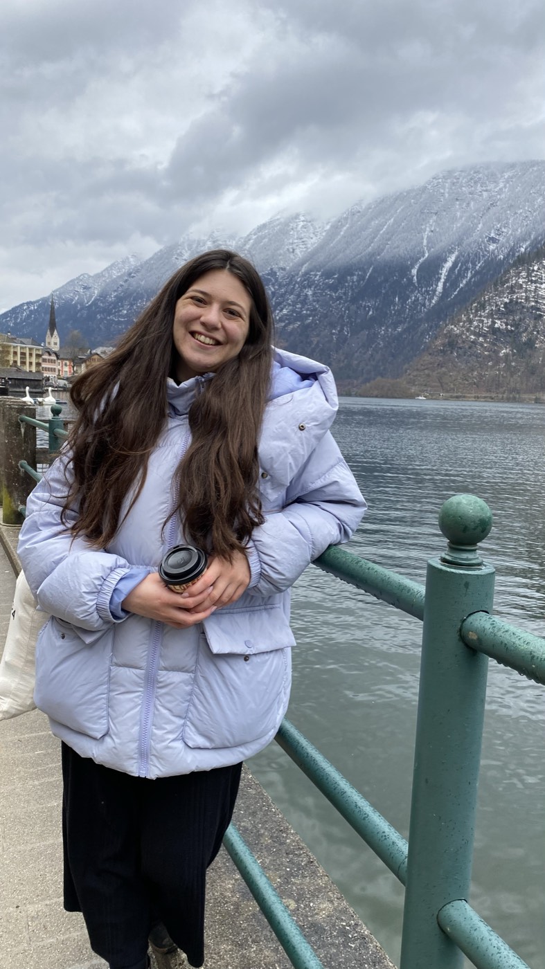 Mariana a sorrir junto ao lago de Hallstatt, com montanhas com neve ao fundo